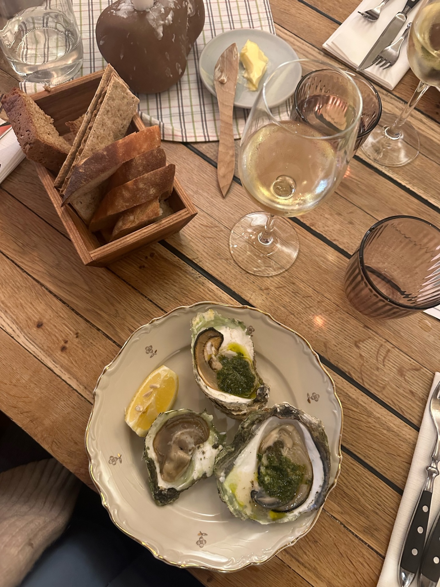 Original photograph of oysters, bread and wine on a wooden restaurant table